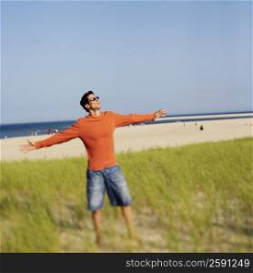 Mature man standing on the beach with his arms outstretched