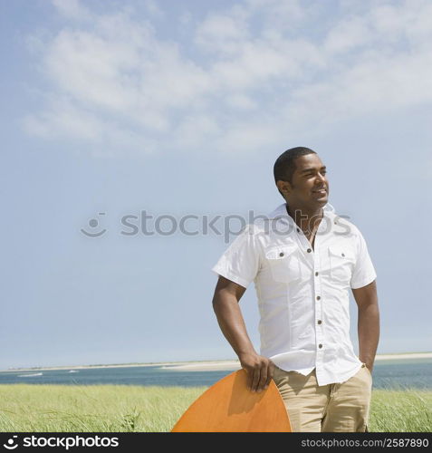 Mature man standing with a surfboard on the beach