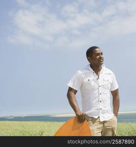 Mature man standing with a surfboard on the beach