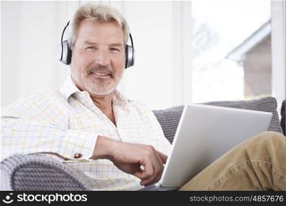 Mature Man Streams Music From Laptop To Wireless Headphones