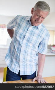 Mature Man Suffering From Backache Whilst Getting Out Of Chair At Home