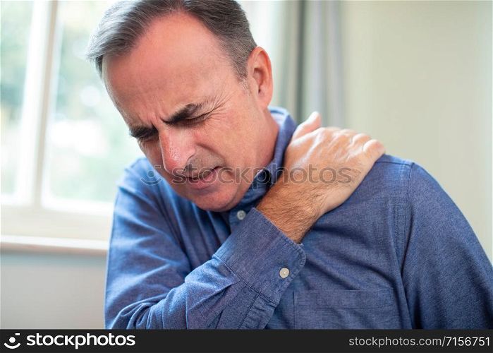 Mature Man Suffering With Trapped Nerve In Shoulder At Home