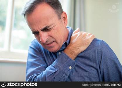 Mature Man Suffering With Trapped Nerve In Shoulder At Home