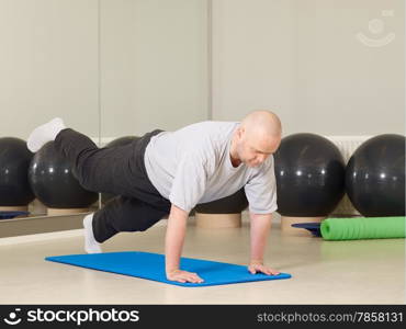 Mature man takes care of his health, he exercise pilates and stretching in a gym