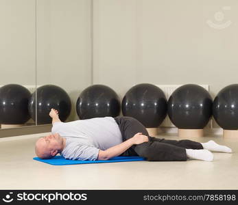 Mature man takes care of his health, he exercise pilates and stretching in a gym