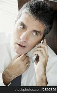 Mature man talking on a mobile phone and adjusting his tie