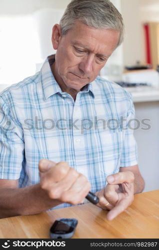 Mature Man Testing Blood Sugar Level At Home