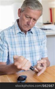 Mature Man Testing Blood Sugar Level At Home