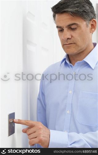 Mature Man Turning Off Light Switch At Home