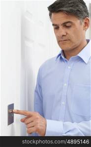 Mature Man Turning Off Light Switch At Home