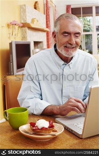Mature man using a laptop and smiling