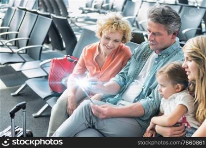 Mature man using digital tablet while his wife and daughter looking in airport