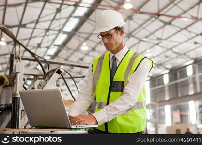 Mature man using laptop in factory