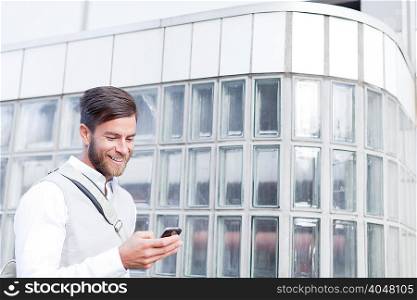 Mature man walking outdoors, using smartphone