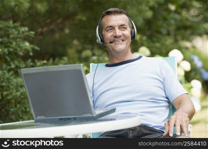 Mature man wearing headset and using a laptop