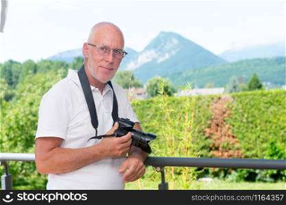 mature man with a dslr camera, outdoors