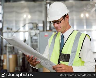 Mature man with blueprint in factory