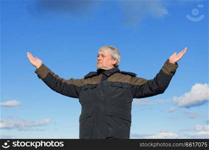 Mature man with grey hair relaxing on the blue sky of the background;