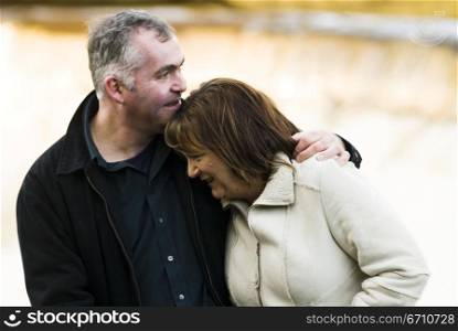 Mature man with his arm around a mature woman and smiling