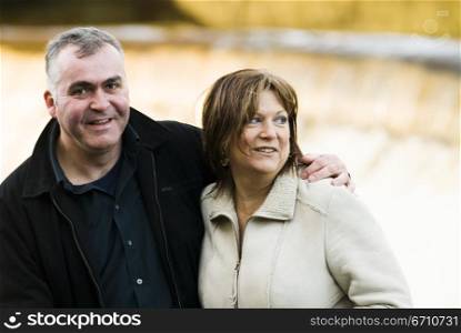 Mature man with his arm around a mature woman and smiling