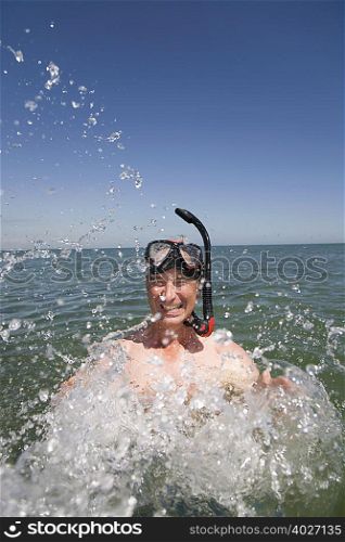 Mature man with snorkel splashing water
