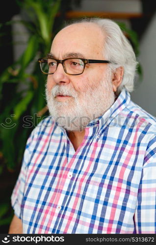 Mature man with white beard and glasses in his home.