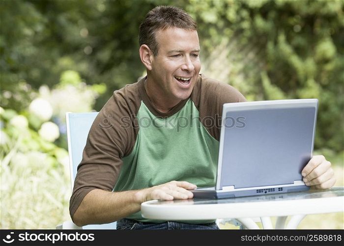 Mature man working on a laptop and laughing