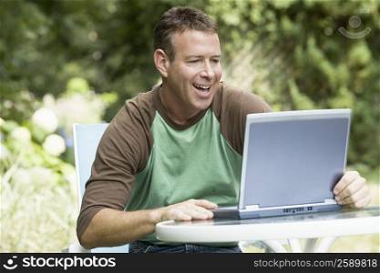 Mature man working on a laptop and laughing