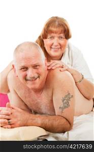 Mature married couple keeps things romatic with massage. Isolated on white.