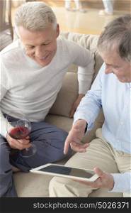 Mature men using digital tablet while sitting on sofa at home