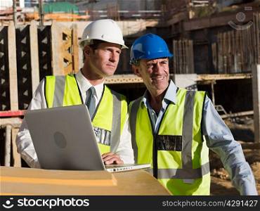 Mature men uusing laptop on construction site