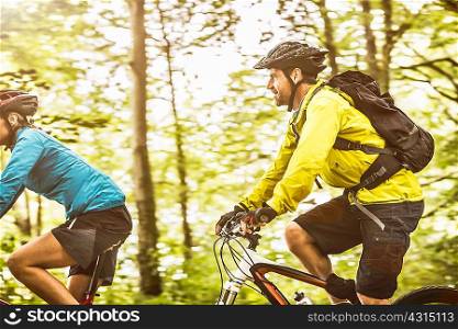 Mature mountain biking couple speed cycling in forest