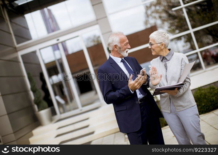 Mature or senior business people talking outdoors and discussing a document