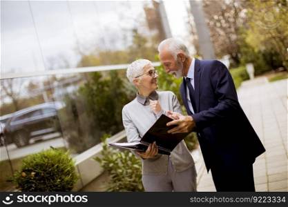 Mature or senior business people talking outdoors and discussing a document