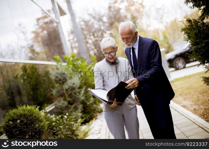 Mature or senior business people talking outdoors and discussing a document