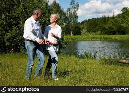 Mature or senior couple being very close to each other at a lake running on the grass on the shore