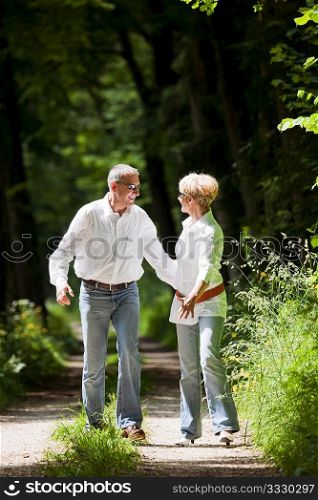 Mature or senior couple deeply in love chasing each other in late spring or early summer
