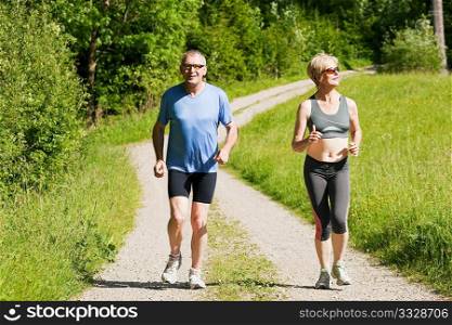 Mature or senior couple doing sport outdoors, jogging