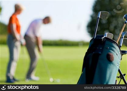 Mature or senior couple playing golf, FOCUS IS ON BAG IN FRONT