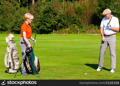 Mature or senior couple playing golf, walking down the course