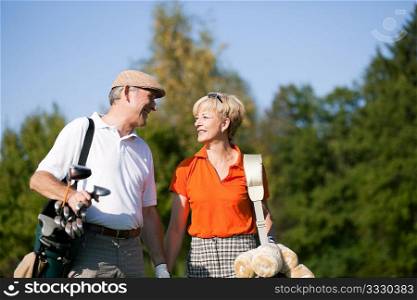 Mature or senior couple playing golf, walking down the course