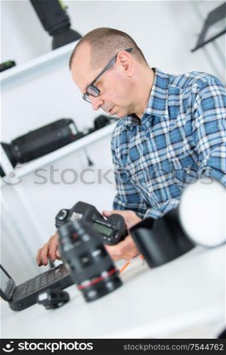 mature photographer cleaning lenses in his studio