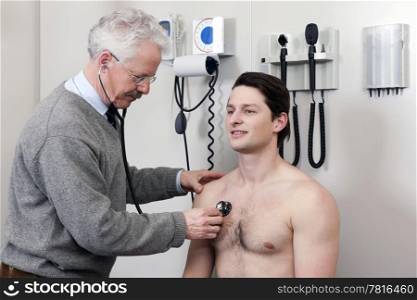 Mature physician examining patient with a stethoscope at clinic