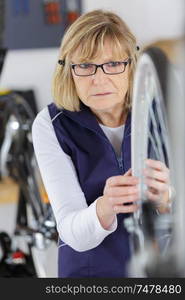 mature positive woman fixing wheels in workshop