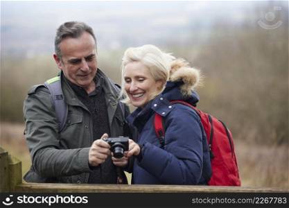 Mature Retired Couple Walk In Fall Or Winter Countryside Taking Photo On Digital Camera