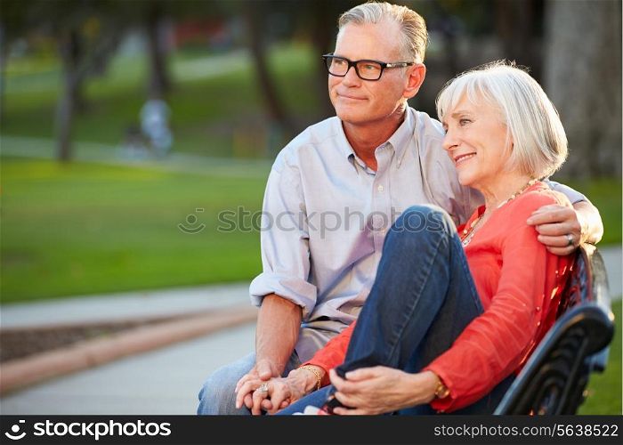 Mature Romantic Couple Sitting On Park Bench Together