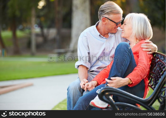 Mature Romantic Couple Sitting On Park Bench Together