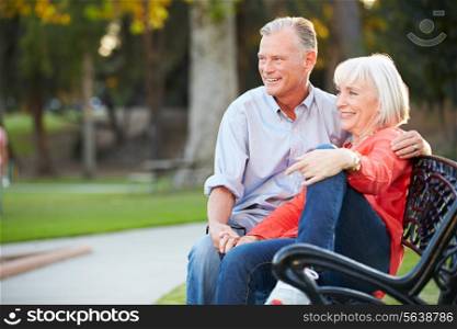 Mature Romantic Couple Sitting On Park Bench Together