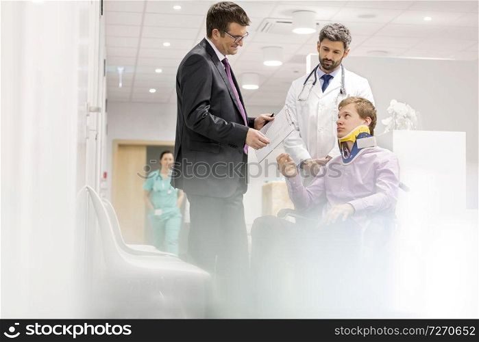 Mature specialist talking to patient on wheelchair at hospital