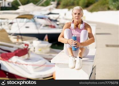 Mature sportswoman taking a break during exercise. Concept of healthy living in the elderly. Senior woman in fitness clothing. Older female doing sport to keep fit.. Senior woman in fitness clothing taking a break during exercise.